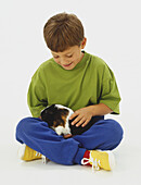 Boy sitting cross-legged stroking guinea pig in his lap