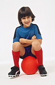 Boy sitting on a red ball