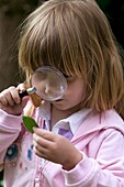 Girl looking at leaf through magnifying glass