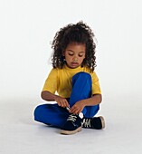 Girl sitting on the floor tying her shoe laces
