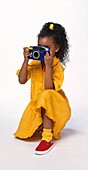 Girl kneeling on one knee holding a camera to her eye