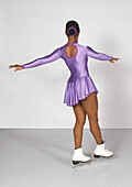 Teenage girl in purple ice skating costume, arms out to side