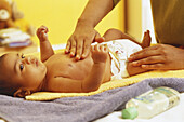 Baby lying on a changing mat having its stomach stroked