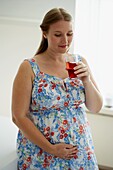 Smiling pregnant woman holding glass of fruit juice