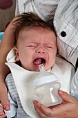 Crying baby being fed with bottle