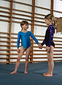 Two young female gymnasts holding hands