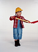 Girl dressed as a builder holding a shovel up