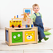 Boy playing with building blocks beside a wooden trunk