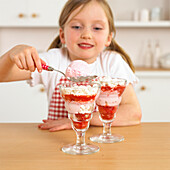 Girl holding spoon of ice cream over glass with ice cream