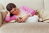 Woman lying down on sofa breastfeeding baby boy