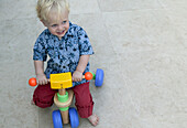 Boy on toy bicycle on patio