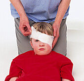 Bandaging boy's injured eye