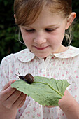 Girl looking at snail on leaf