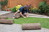 Man laying new turf in a small garden