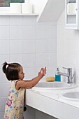 Young girl washing her hands at a sink