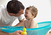 Mature adult father giving baby son bath