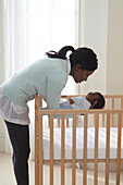 Woman holding baby boy above cot