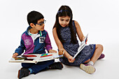 Brother and sister sitting together reading