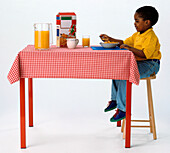 Young boy sitting at a table eating breakfast