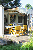 Table and yellow chairs on terrace outside summerhouse