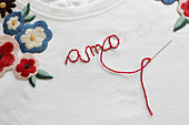 Stickerei mit Blüten und Schriftzug 'amore'