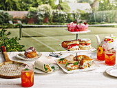 Afternoon tea with sandwiches, shortcake and cupcakes on a tennis court