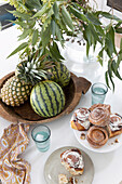 Yeast pastries, fruit bowl and leafy branches on kitchen island