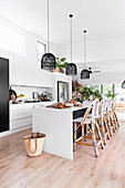 Kitchen island with bar stools, black pendant lights above in open-plan kitchen