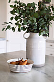 Bowl with pears and ceramic vase with eucalyptus branches on kitchen table