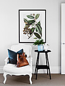 White armchair with throw pillows and bag next to a side table with an indoor plant