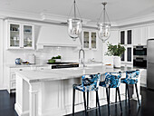 Kitchen island with Carrara marble worktop and bar stools with blue and white upholstery