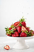 Erdbeeren auf einem weißen Teller mit Wassertropfen vor weißem Hintergrund