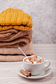 Hot chocolate with marshmallow and pile of warm knitted clothes