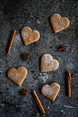 Heart-shaped gingerbread cookies between anise stars and cinnamon sticks