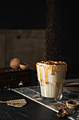 Caramel milkshake with caramel drips, nuts and cocoa powder