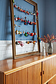 Old picture frame with vintage Christmas baubles on sideboard