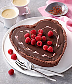 Schokoladenkuchen in Herzform mit Trüffelcreme und Himbeeren