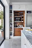 Shelves of kitchen appliances that can be concealed behind doors integrated into kitchen units