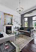 Elegant lounge with grey sofas and antique mirror above fireplace