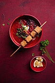 Vegan beetroot and carrot soup with fried tofu on a skewer