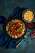 Vegetable tagine with couscous, pomegranate seeds, fresh coriander and olives