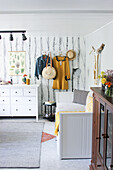 Couch and chest of drawers in living room and coat rack on wallpapered wall