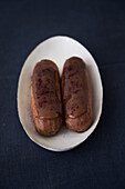 Mocha éclairs on a plate against a dark background