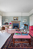 Upholstered furniture, antiques and fireplace in living room with blue walls
