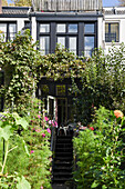 Vorgarten mit Sommerblumen, Treppen führen zum Hauseingang
