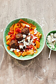 A vegetable noodle bowl with lentils, meatballs and feta cheese