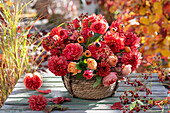 Herbstgesteck aus Dahlien, Rosen und Hagebutten im Korb