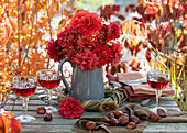 Herbststrauß aus roten Dahlien und Hagebutten in Kranz aus Gräsern