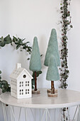 Decorative miniature winter village on round table with felt pine trees and white house