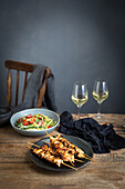Hähnchenspieße mit Salat und Wein auf rustikalem Holztisch